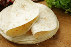 stack of homemade whole wheat flour tortillas on a wooden table